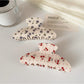 Beau hair claw clip held in hand displaying size and printed pattern details
