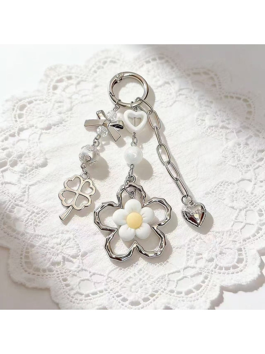 Flat lay of minimalist flower charm keychain with silver ring and white background