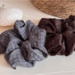 Gifty scrunchie wrapped around a ponytail on a model with dark hair