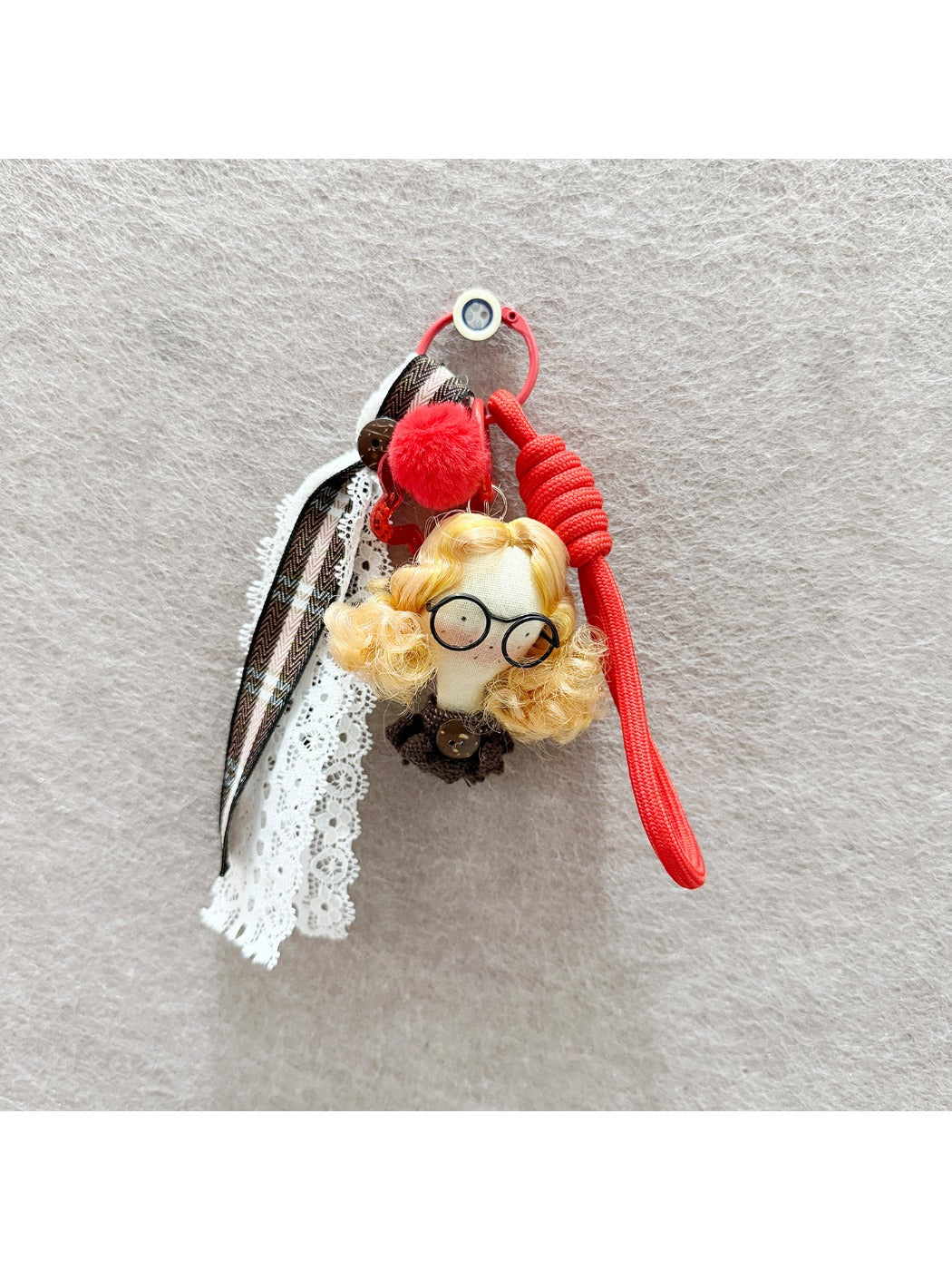 Fabric curly hair doll keychain held in hand showing size and craftsmanship