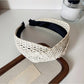 Model adjusting the Gifty wide crisscross headband in natural light