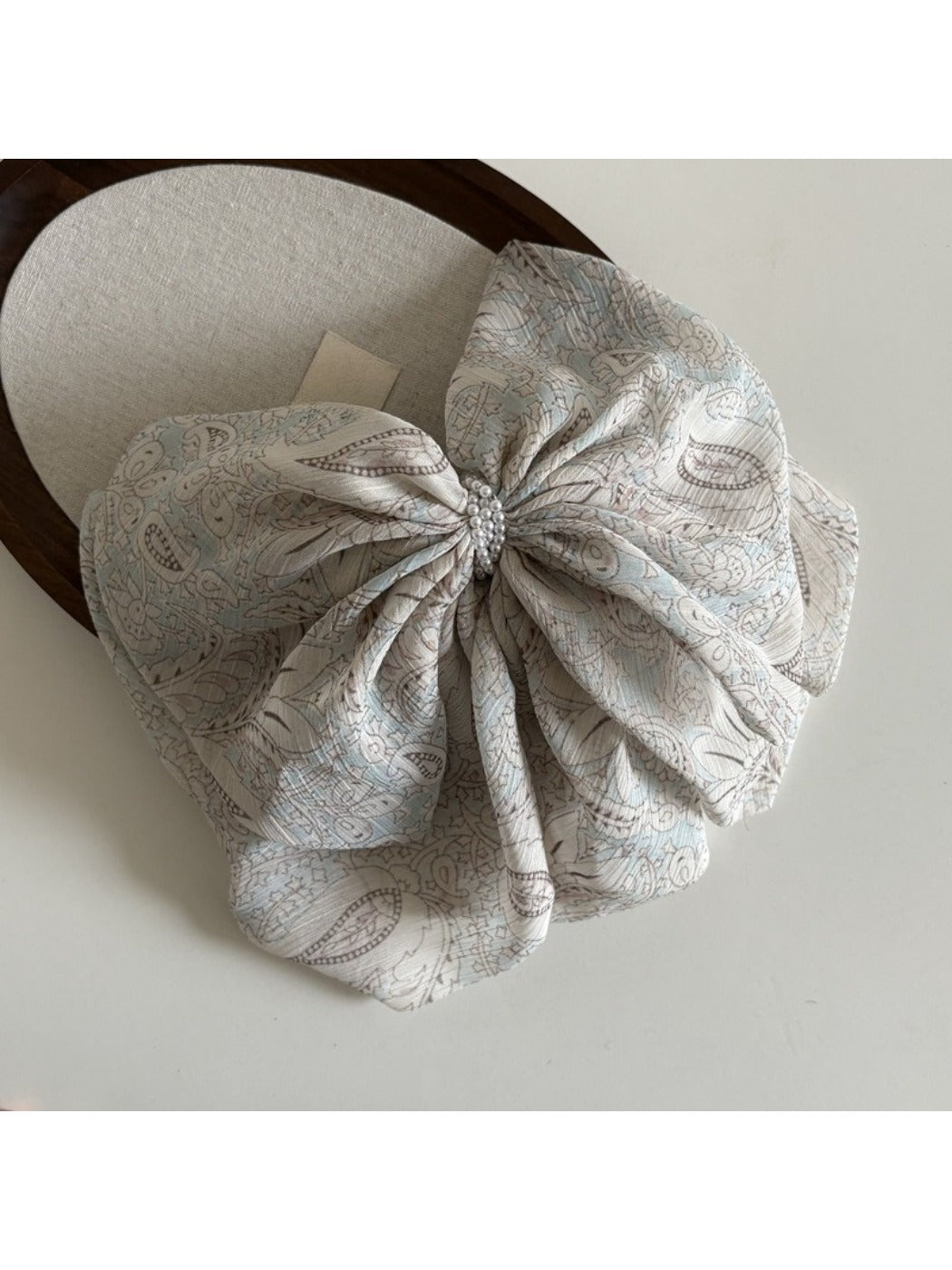 Beau chiffon bow shaped claw clip worn in model's hair from back view