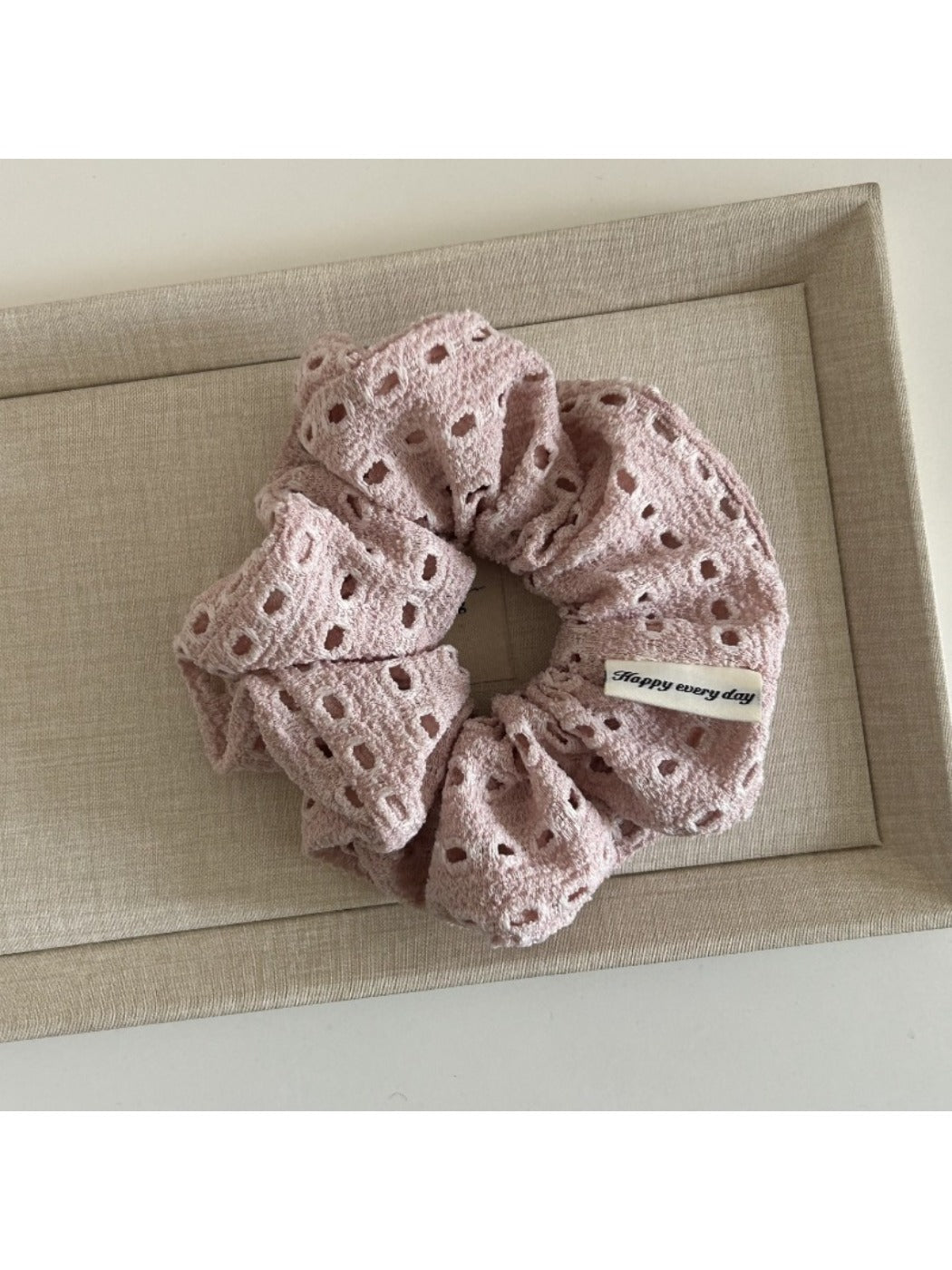 Soft beige scrunchie styled in a ponytail on dark hair