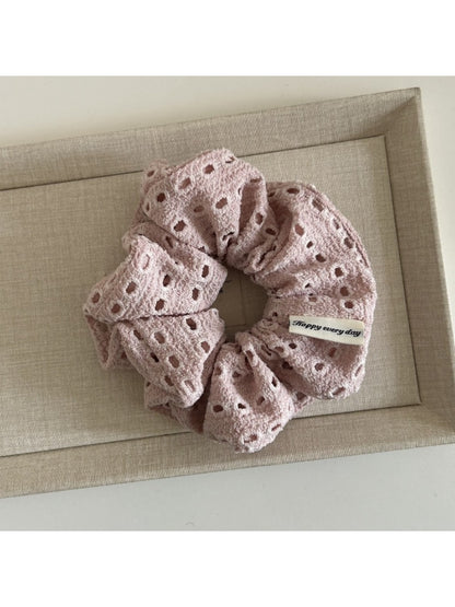 Soft beige scrunchie styled in a ponytail on dark hair