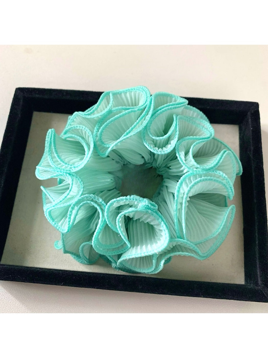Gifty ruffle scrunchie shown in natural light emphasizing fabric softness
