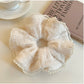 Beige ruffle scrunchie styled on a wrist as an accessory
