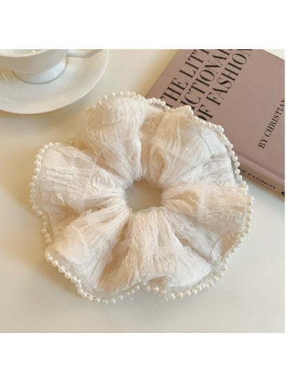 Beige ruffle scrunchie styled on a wrist as an accessory