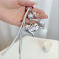 Silver heart keychain attached to a set of keys on a wooden surface