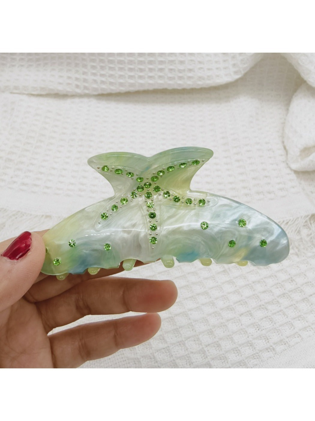 Beau rainbow claw clip positioned on a wooden surface for texture contrast