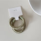 Model styling hair with Gifty satin hair tie in natural outdoor setting