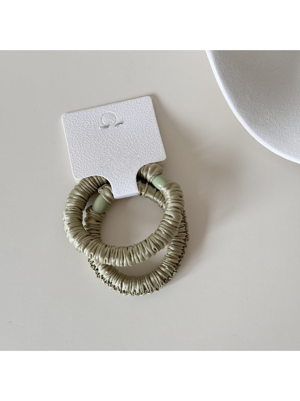Model styling hair with Gifty satin hair tie in natural outdoor setting