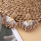 Close-up of earedge fan-shaped raffia earrings highlighting intricate weaving details