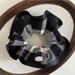 Flat lay of black edge black and white check scrunchie with soft fabric texture