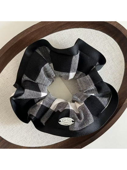 Flat lay of black edge black and white check scrunchie with soft fabric texture
