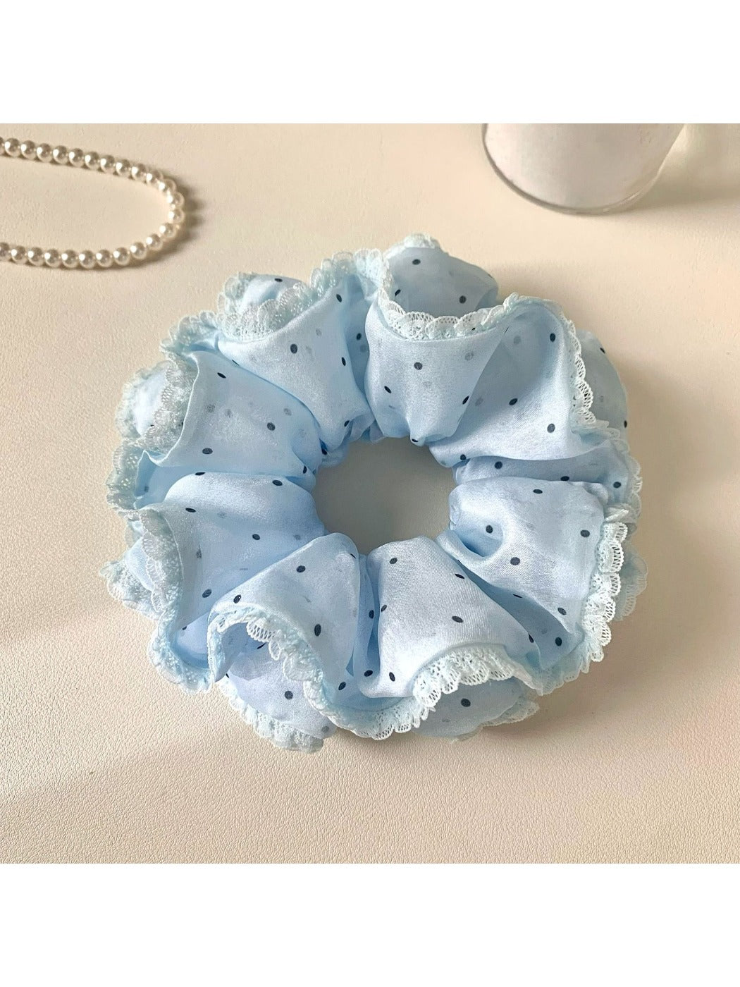 Pink polka dot scrunchie styled on a wrist as a bracelet