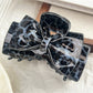 Beau classic bow claw clip with leopard print on a neutral fabric background