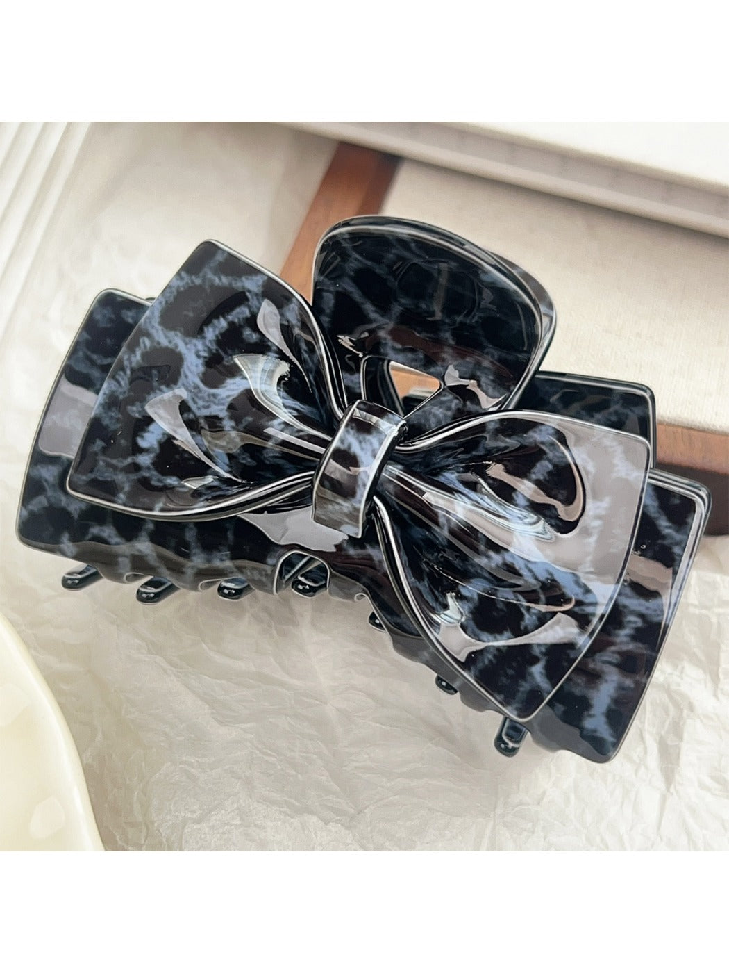 Beau classic bow claw clip with leopard print on a neutral fabric background