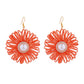 Earedge raffia woven flower-shaped earrings hanging from a jewelry stand