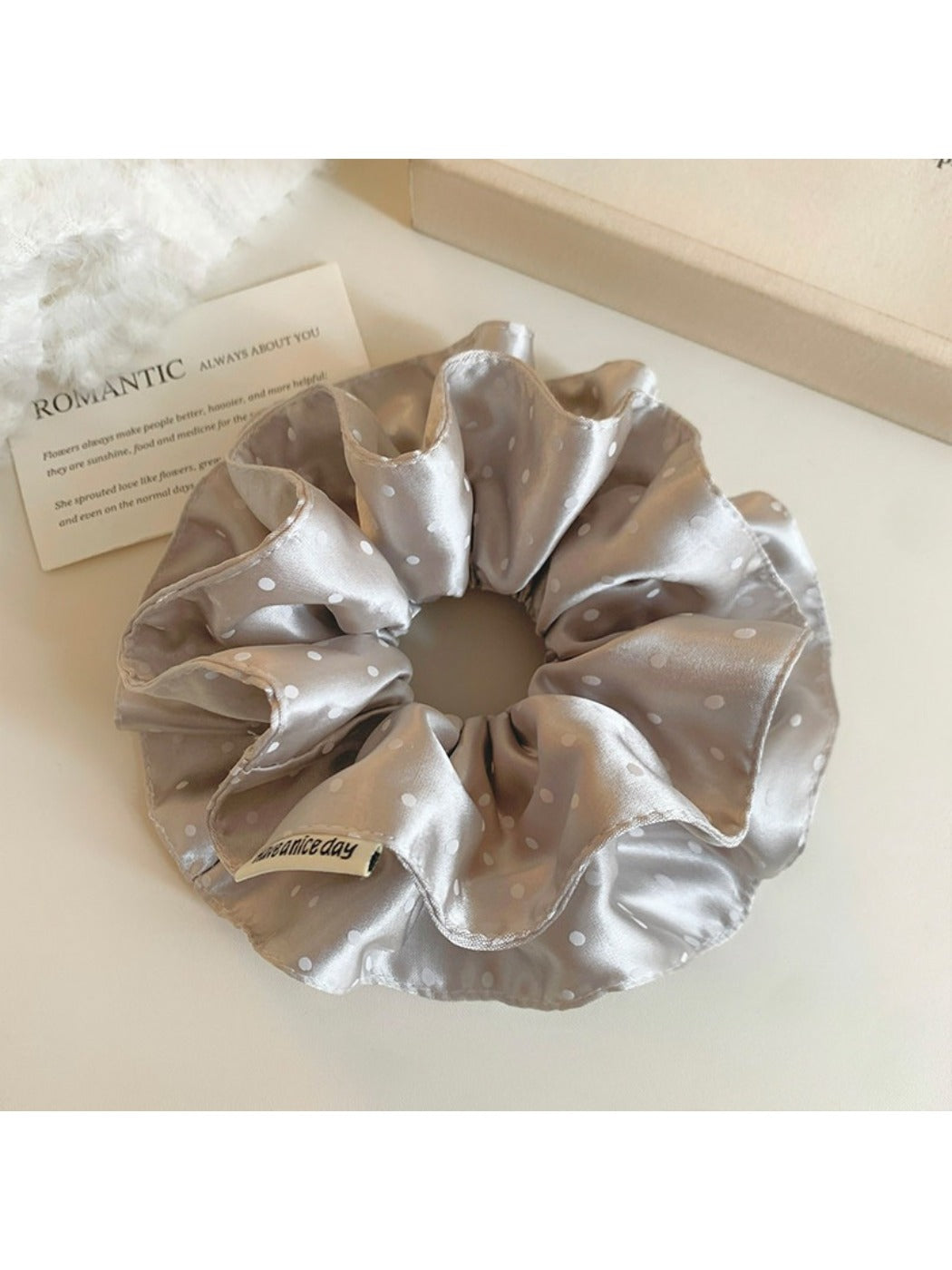 Gifty satin polka dot scrunchie displayed flat to show full circular shape and fabric texture