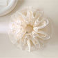 Close-up of white lace scrunchie showing intricate layered fabric details