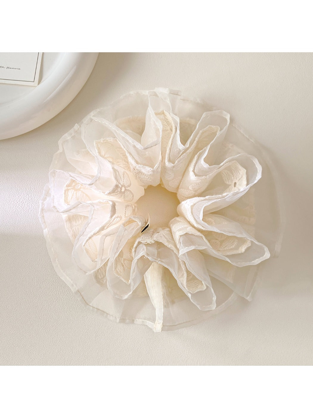 Close-up of white lace scrunchie showing intricate layered fabric details