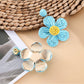 Earedge flower shaped drop earrings displayed on a wooden surface