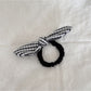 Gifty hair tie with red bow embellishment shown in natural light on a white background
