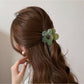 Beau mini flower claw clip holding a small section of hair