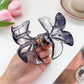 Beau flower claw clip held in hand displaying size and vibrant colors