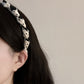 Black and white braided fabric headband with a twisted knot design