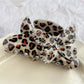 Beau claw clip resting on fabric, showing texture and butterfly adornment