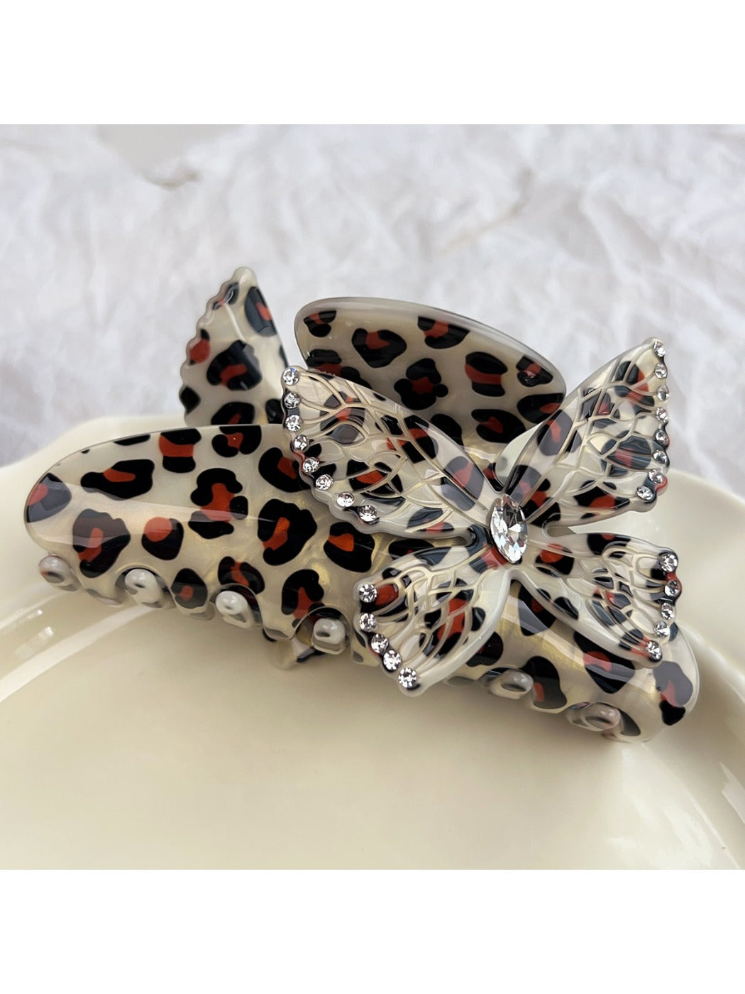 Beau claw clip resting on fabric, showing texture and butterfly adornment