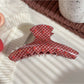 Beau hair claw clip resting on white surface highlighting strawberry design