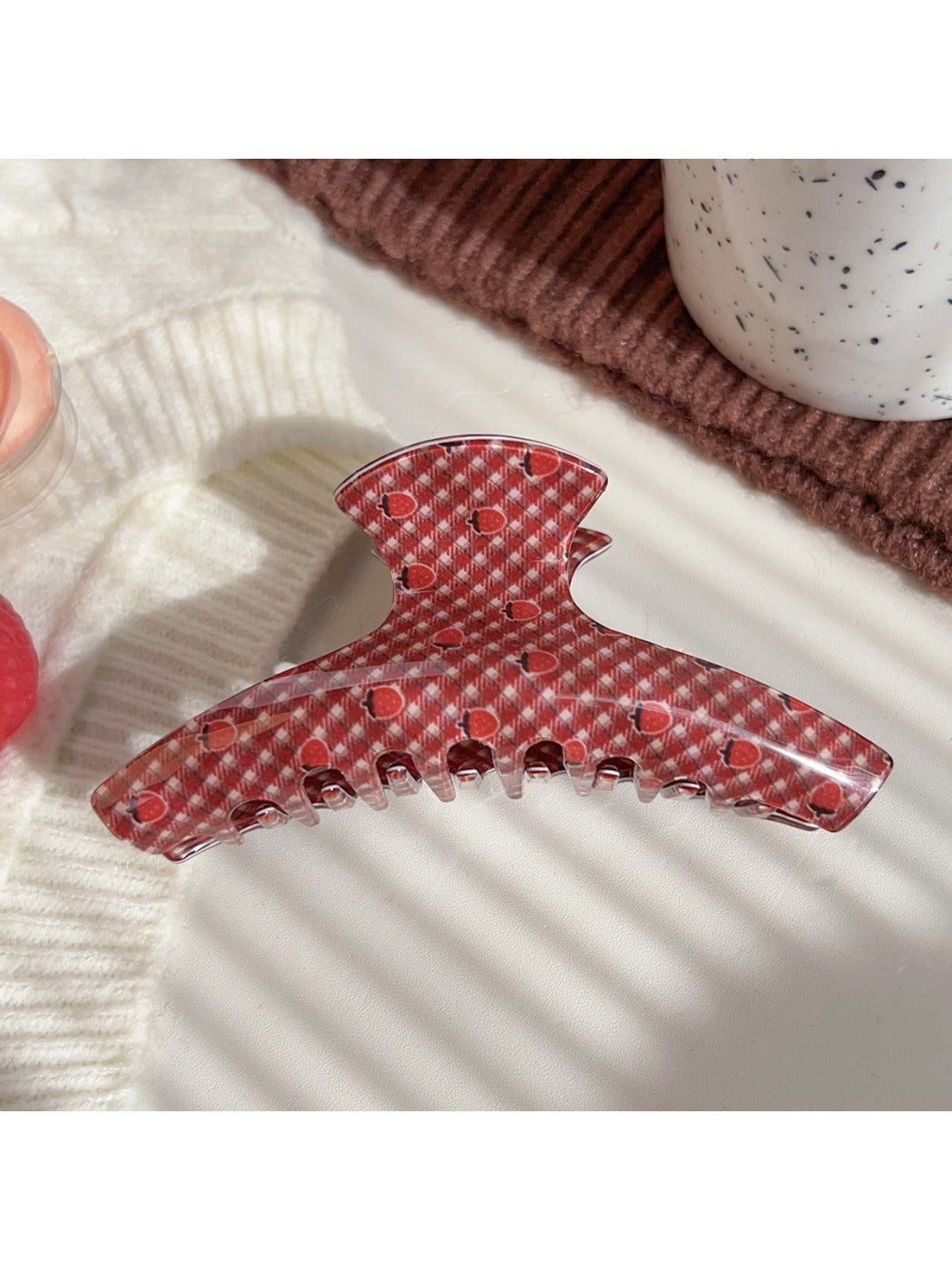 Beau hair claw clip resting on white surface highlighting strawberry design