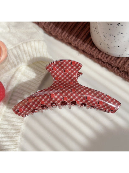 Beau hair claw clip resting on white surface highlighting strawberry design
