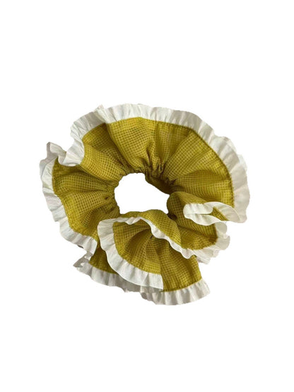Green plaid scrunchie worn on a wrist showing white trim detail