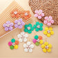 Close-up of Earedge raffia flower-shaped earrings with natural beige fibers and gold-tone studs