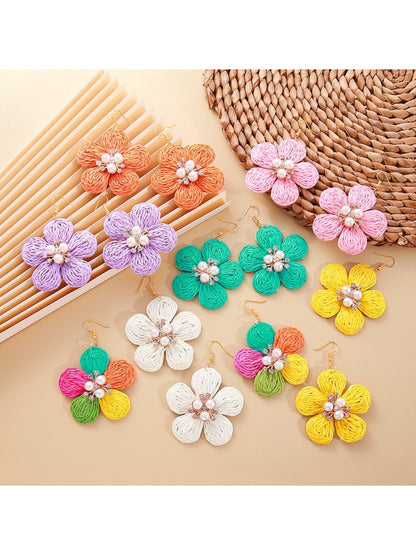 Close-up of Earedge raffia flower-shaped earrings with natural beige fibers and gold-tone studs