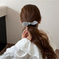 Gifty hair tie with plaid pattern and red bow displayed on a wooden table