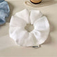 Model wearing a minimalist solid color ruched scrunchie in a ponytail