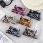 Close-up of Beau leopard print claw clip with butterfly decoration on a white background