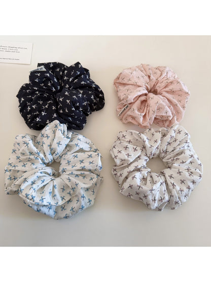 Close-up of Gifty elegant ditsy floral scrunchie with small pink and white flowers on beige fabric