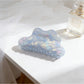 Beau mermaid claw clip with holographic finish resting on fabric