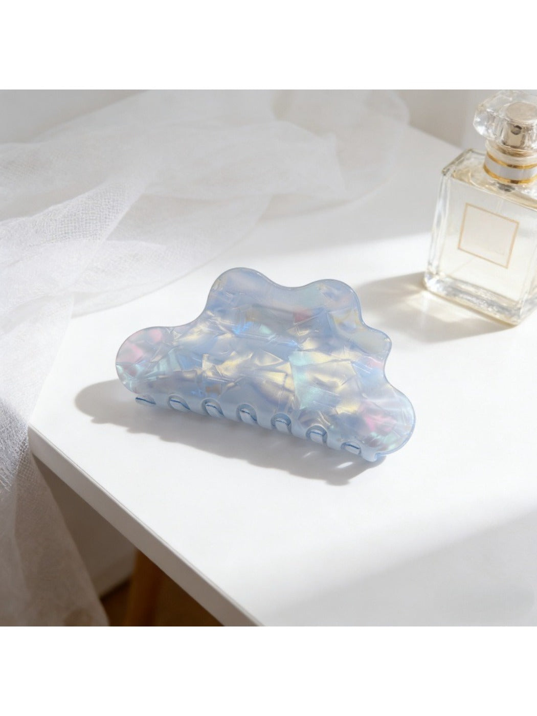 Beau mermaid claw clip with holographic finish resting on fabric