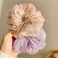 Multiple solid color ruched scrunchies arranged in a row showcasing color options