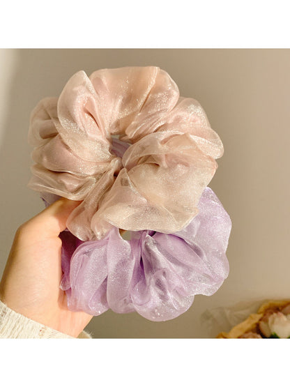 Multiple solid color ruched scrunchies arranged in a row showcasing color options