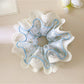 Blue scrunchie with delicate lace trim on a white background