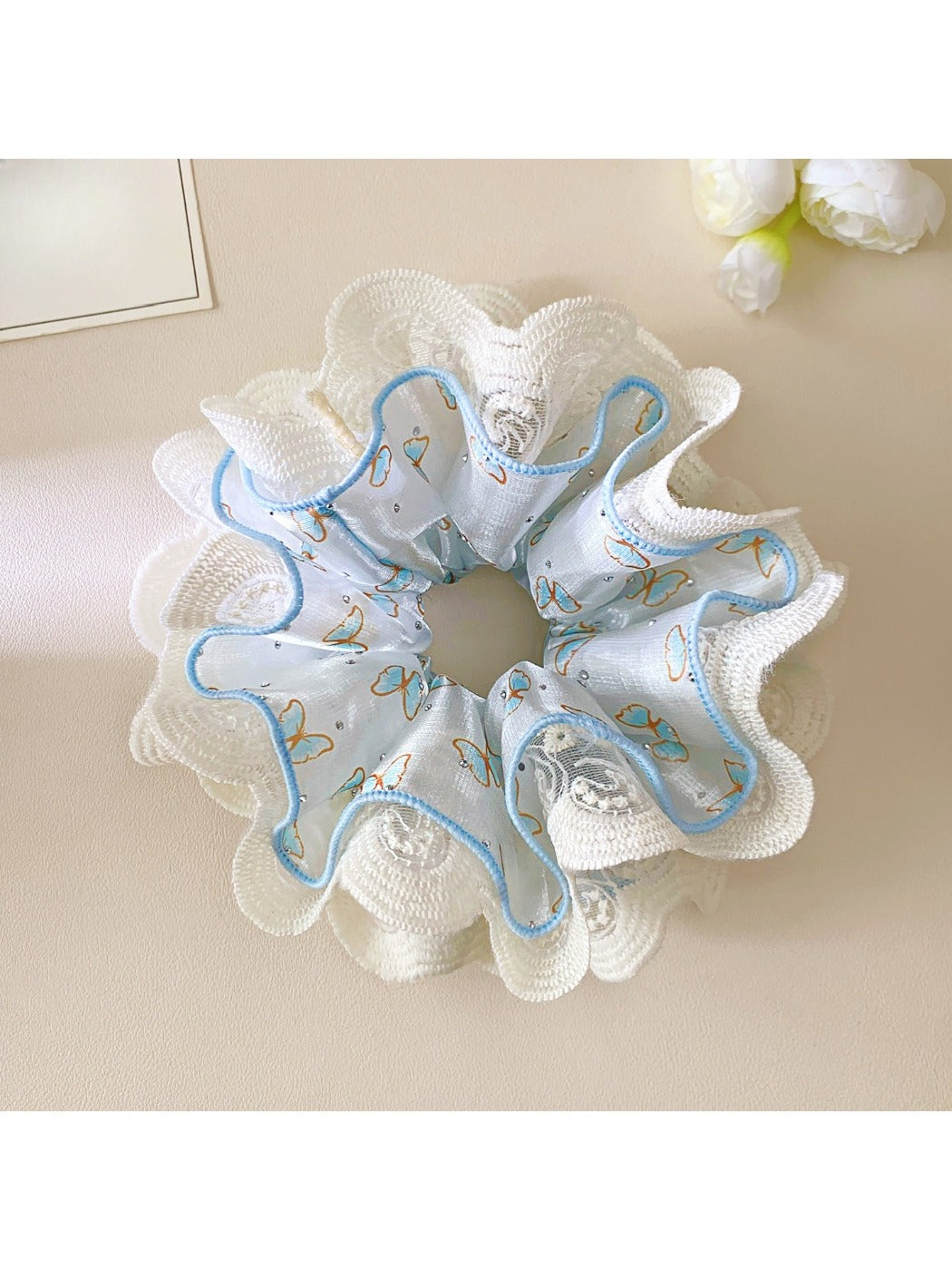 Blue scrunchie with delicate lace trim on a white background