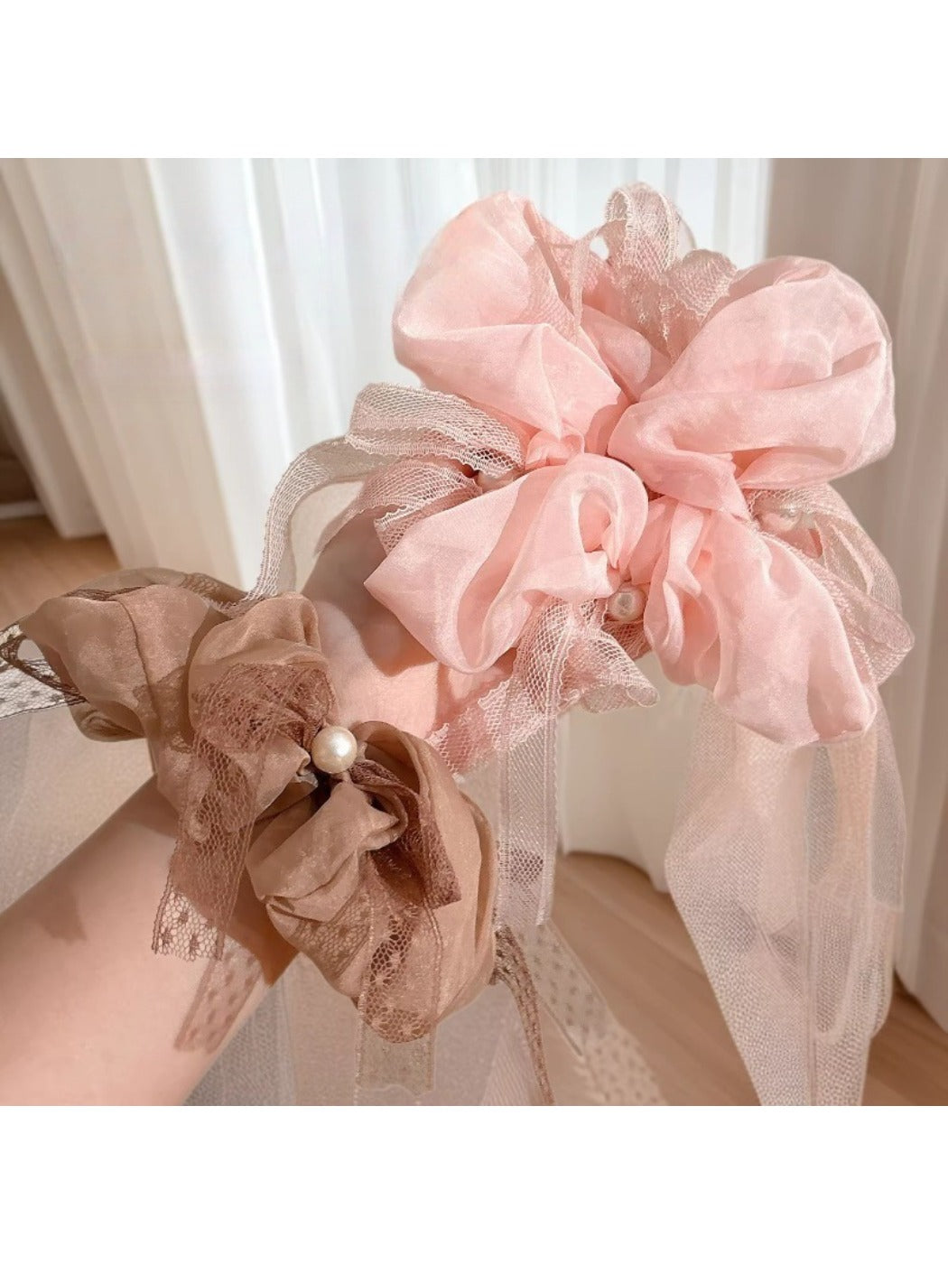 Close-up of Gifty elegant scrunchie with a large bow in soft pink fabric