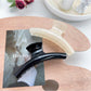 Pastel curved claw clip held in hand demonstrating size and grip